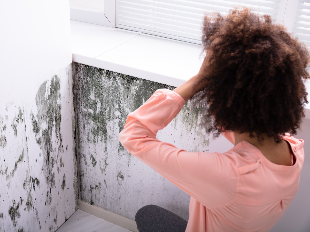 Woman overwhelmed by mold on the wall of her home